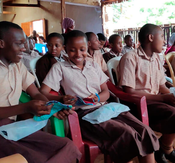 Schoolgirls in a Kenyan classroom examining Padmad reusable pads