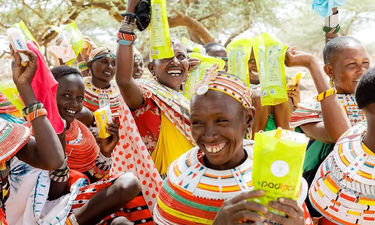 Group of Kenyan women and teens smiling and proudly holding Padmad reusable sanitary kits.