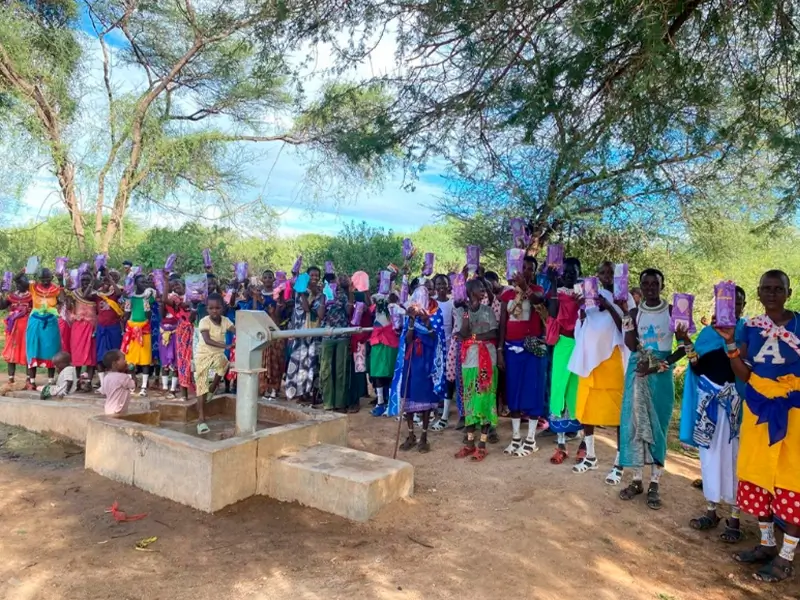 Samburu women and girls holding PadMad reusable pads next to a water pump, illustrating the link between menstrual health and hygiene and clean water. Photo credits: Solomon from The Samburu Project